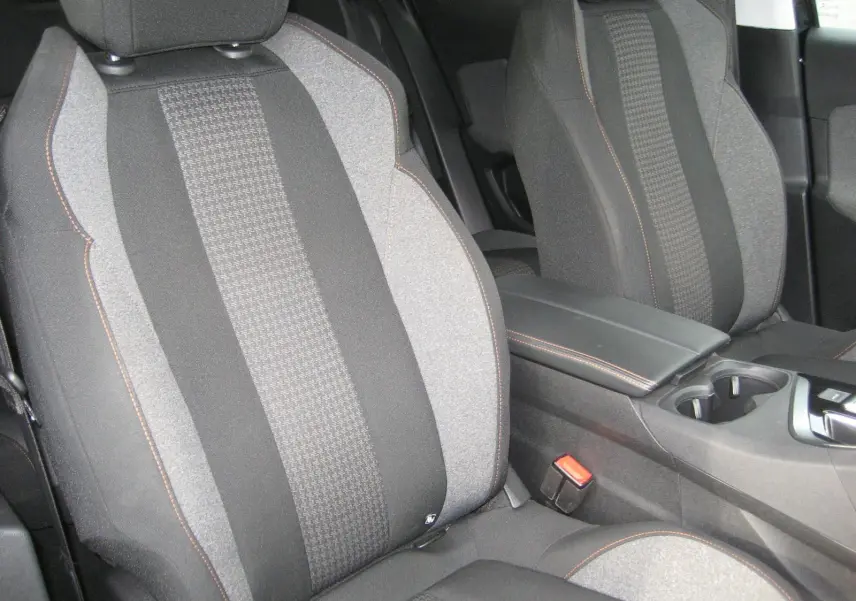 Gros plan sur les sièges avant gris et noirs du Peugeot 3008 Business 2020 avec surpiqûres orange et console centrale visible.