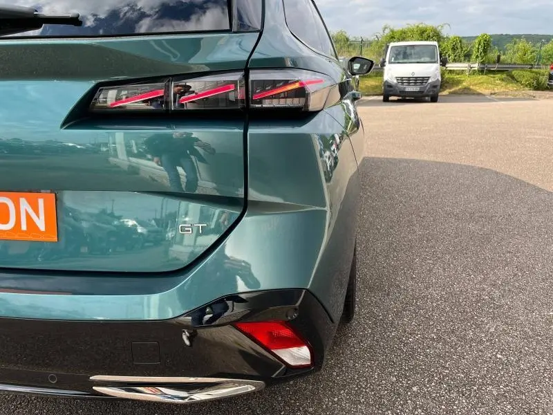 Vue arrière droite d'une Peugeot 308 SW GT bleu Avatar avec feux arrière LED et détails chromés au pare-chocs.