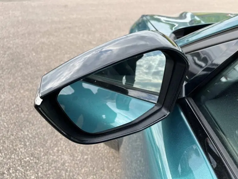 Rétroviseur extérieur noir brillant côté gauche d'une Peugeot 308 SW 2023 Bleu Avatar avec carrosserie visible en arrière-plan.