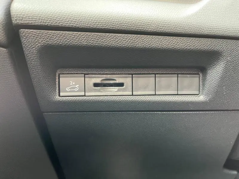 Gros plan sur les commandes noires sous le tableau de bord du PEUGEOT 308 SW Bleu Avatar, côté conducteur.