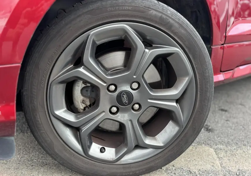 Gros plan sur la roue avant droite d'un Ford EcoSport rouge 2019 avec jante alliage et pneu Hankook.