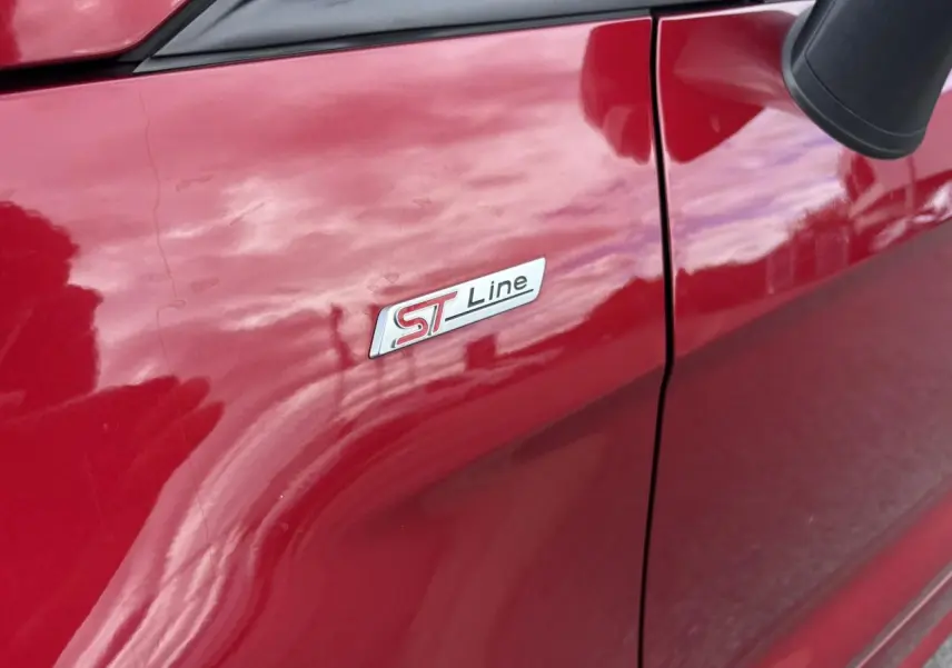Gros plan sur l'écusson ST-Line côté gauche d'un Ford EcoSport rouge métallisé 2019.