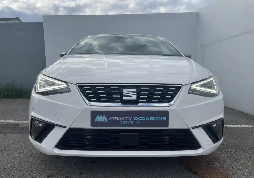 Vue frontale d'une SEAT IBIZA blanche 2025 avec feux LED triangulaires et calandre noire distinctive.