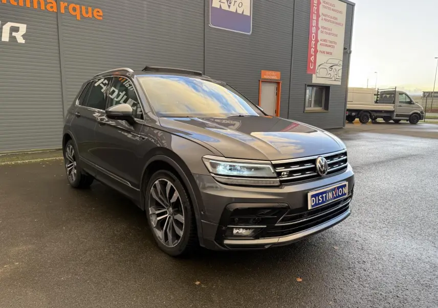Volkswagen Tiguan gris Indium métallisé en 3/4 avant droit avec jantes alliage et calandre R-Line visible.