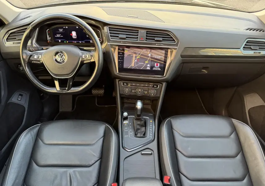 Vue intérieure frontale du Volkswagen Tiguan 2019, montrant le tableau de bord, volant cuir multifonctions et sièges sport noirs.