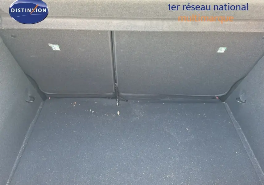 Coffre vide de Renault Clio V rouge flamme, vue intérieure arrière avec banquette rabattue partiellement visible.