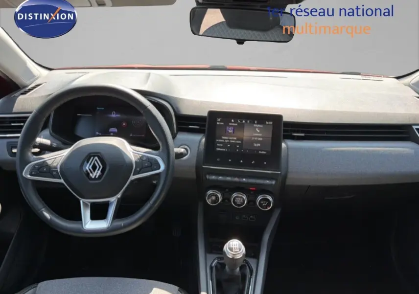 Vue intérieure avant de la Renault Clio V rouge flamme, tableau de bord moderne avec écran tactile et volant multifonction.