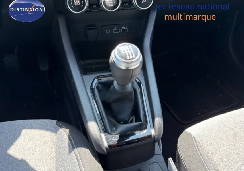 Le levier de vitesse manuel de la Renault Clio V Evolution TCe 90, entouré de la console centrale et des sièges gris.