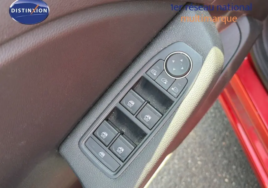 Gros plan sur les commandes des vitres électriques côté conducteur d’une Renault Clio V rouge flamme, porte ouverte.