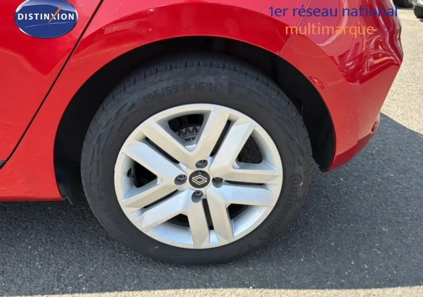 Gros plan sur la roue arrière droite d'une Renault Clio V rouge flamme, avec jante alliage et logo Renault visible.