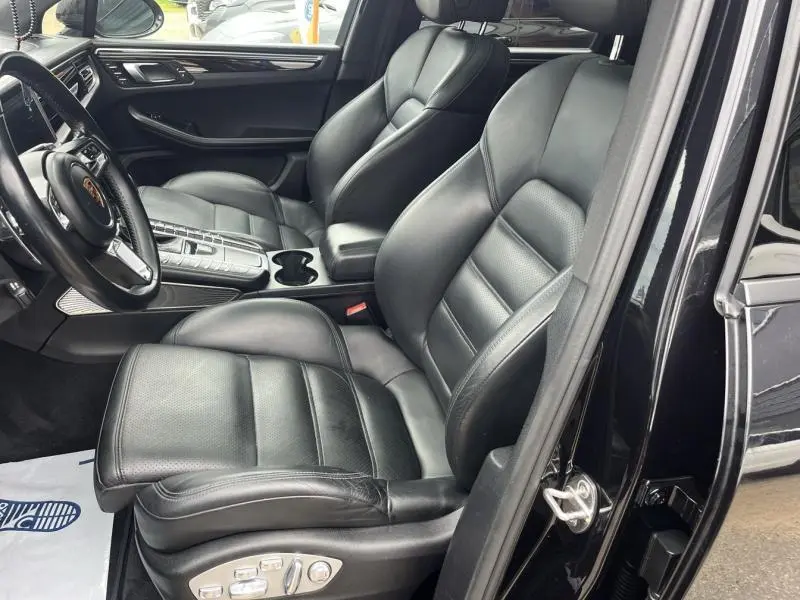 Vue intérieure côté conducteur du Porsche Macan 2.0 noir avec sièges cuir noir et console centrale détaillée.