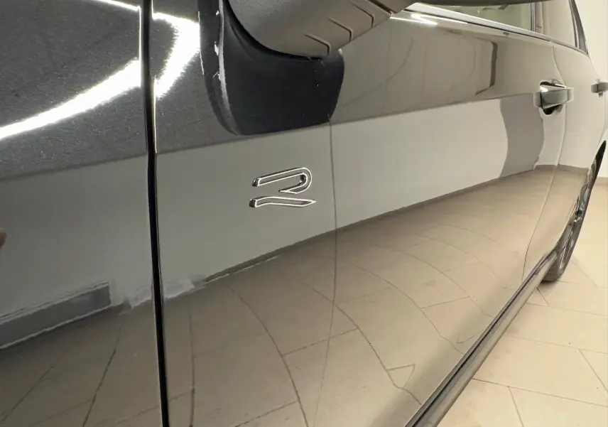 Gros plan sur la porte côté gauche noire grenadille d’une Volkswagen Golf 2.0 TDI R-Line avec logo R brillant.