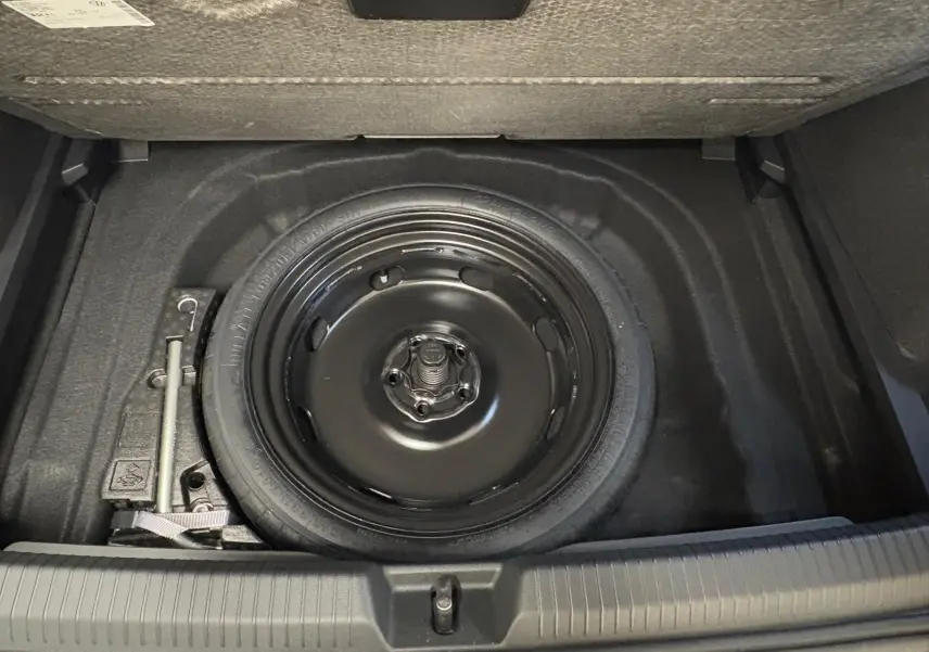 Vue plongeante sur la roue de secours compacte noire dans le coffre d'une Volkswagen Golf 2.0 TDI 150 DSG7 R-Line.