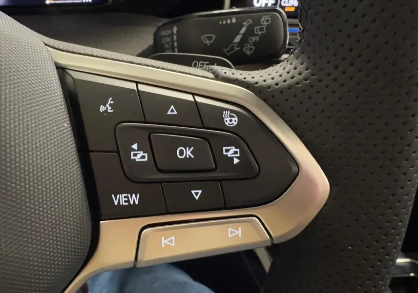 Gros plan sur les commandes multifonctions en cuir perforé du volant chauffant de la Volkswagen Golf 2026 noir Grenadille.