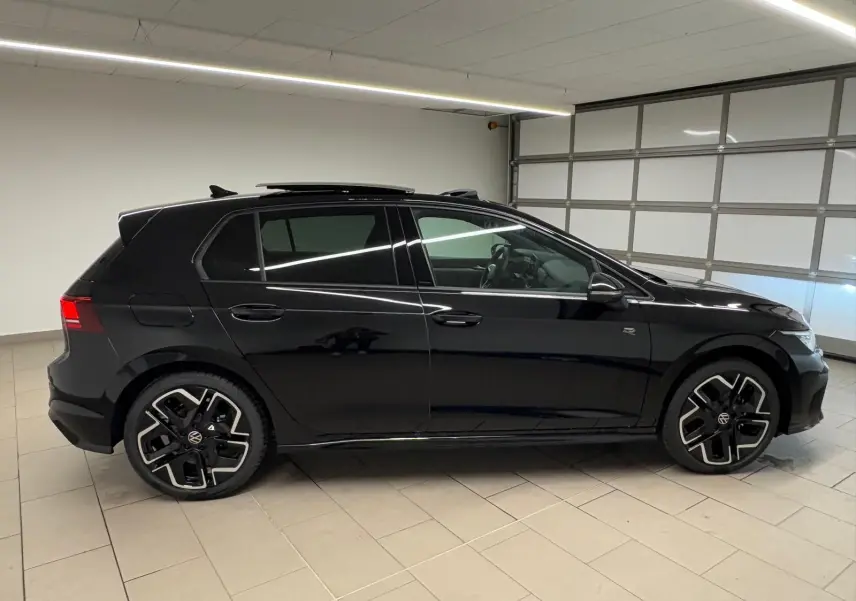 Volkswagen Golf 2.0 TDI R-Line noir grenadille vue de profil côté gauche en intérieur, toit ouvrant partiellement ouvert.