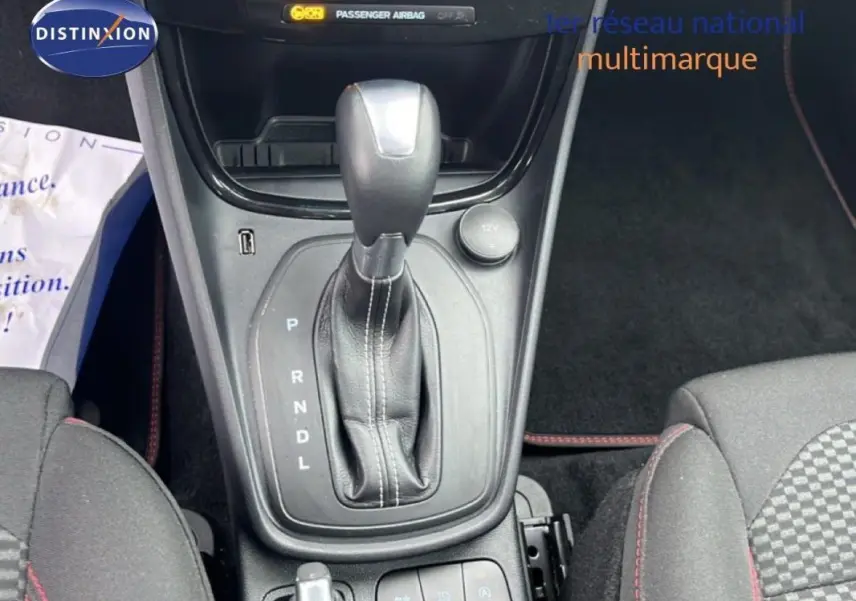 Vue rapprochée de la console centrale du Ford Puma 2024, boîte auto avec levier en cuir et sièges tissu gris foncé.