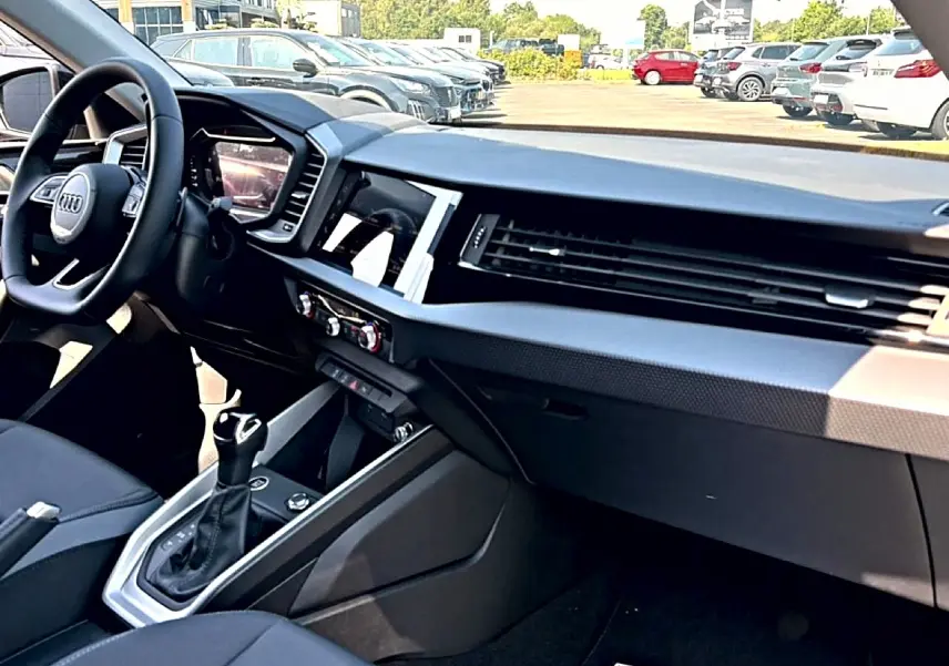 Intérieur noir de l'Audi A1 Sportback 2026 vu côté passager, avec tableau de bord moderne et levier de vitesse cuir.