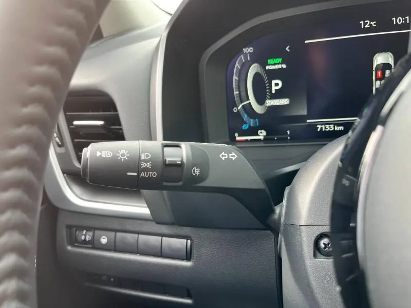 Gros plan sur la manette de commandes d'éclairage à gauche du volant dans le tableau de bord du Nissan Qashqai noir 2024.