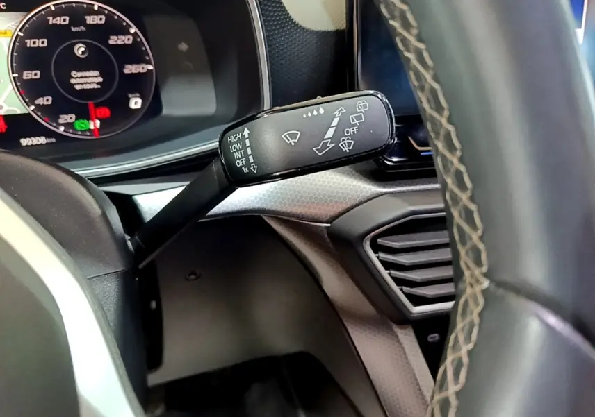 Gros plan sur la manette d'essuie-glace à gauche du volant cuir du tableau de bord d'une SEAT Leon gris clair 2022.