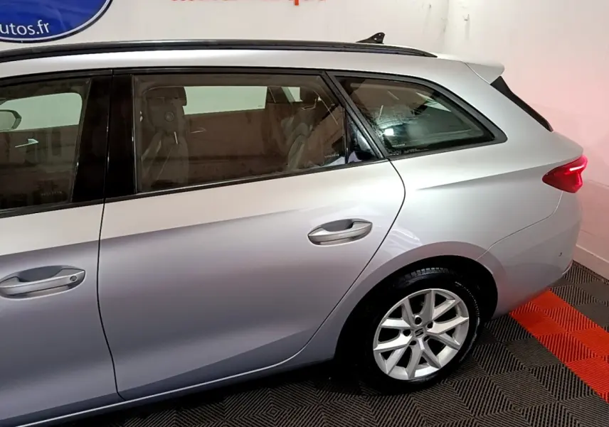 Vue latérale droite arrière d'une SEAT LEON gris clair avec jante alliage et feux arrière LED allumés.