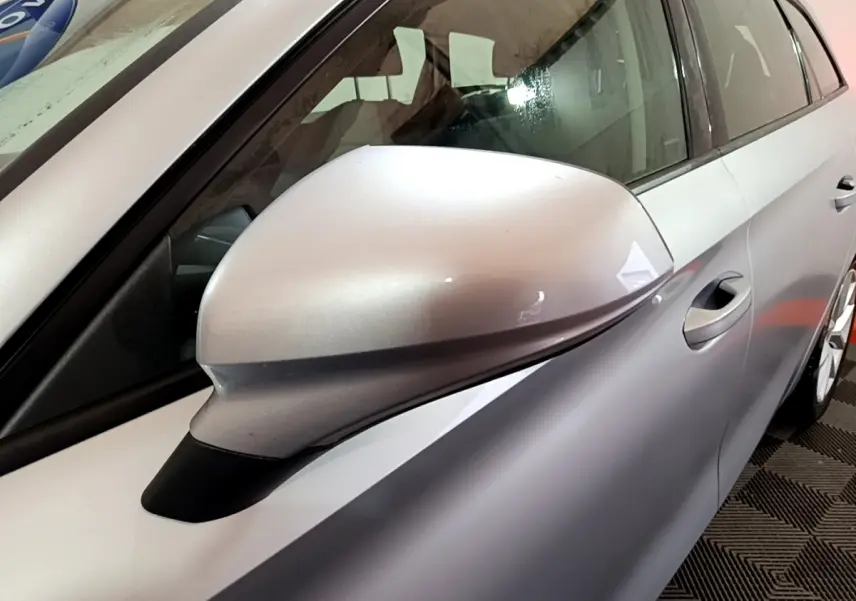 Gros plan sur le rétroviseur côté gauche gris clair du SEAT LEON 2022, avec partie de la porte visible.