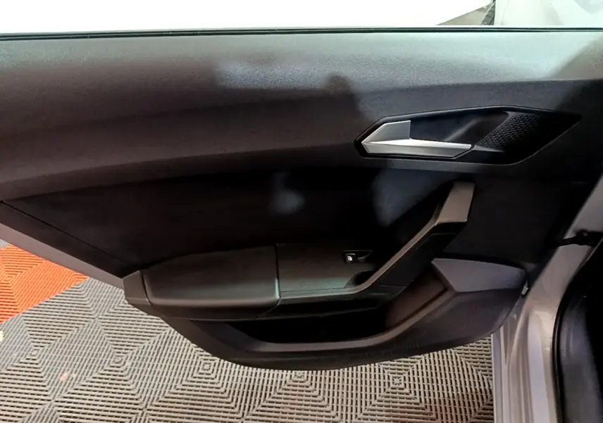 Détail de la porte côté conducteur noire du SEAT LEON gris clair 2022 avec poignée argentée et commande de vitre.