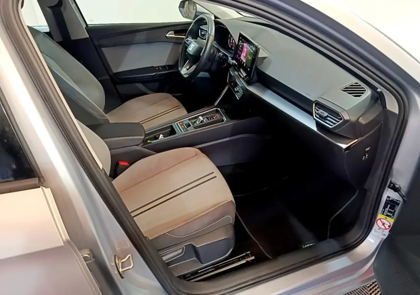 Intérieur côté conducteur du SEAT Leon gris clair 2022, avec tableau de bord moderne et écran tactile central visible.