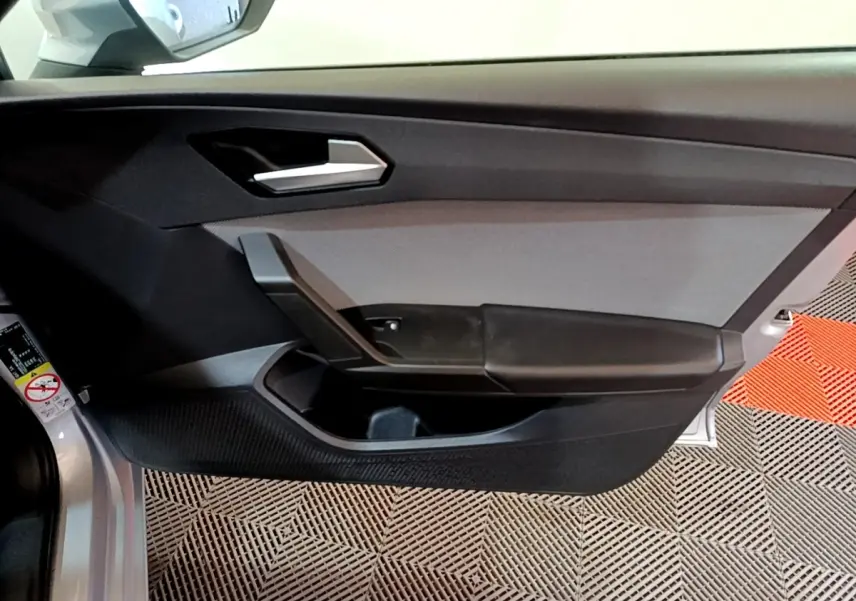 Porte intérieure côté conducteur gris clair de la SEAT LEON 2022 avec poignée argentée et rangement intégré.