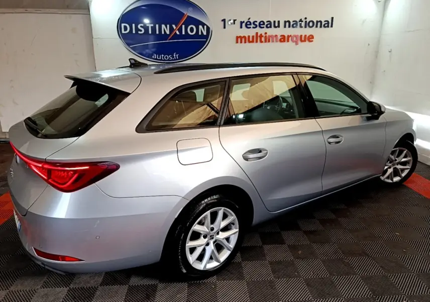 SEAT LEON gris clair en break vu de 3/4 arrière droit dans un showroom avec logo Distinxion en arrière-plan.