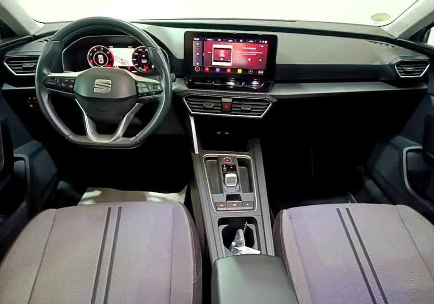 Intérieur de la SEAT LEON 2.0 TDI 2022 vu de face, tableau de bord noir avec écran tactile central et sièges gris.
