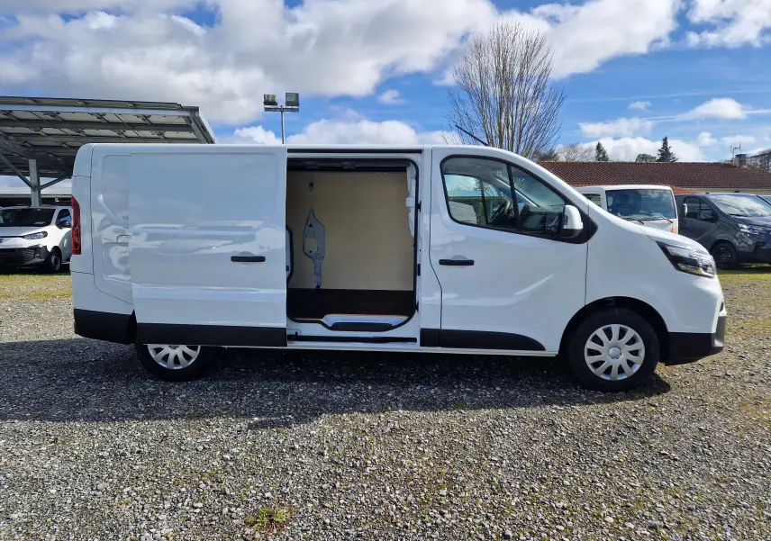 Nissan Primastar blanc vu de profil droit avec porte latérale coulissante ouverte montrant l’intérieur boisé du coffre.