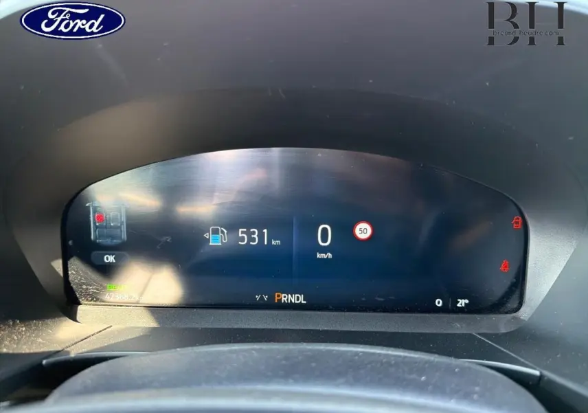 Tableau de bord numérique du Ford Kuga 2025 affichant autonomie, vitesse et indicateurs, vu de face depuis le siège conducteur.