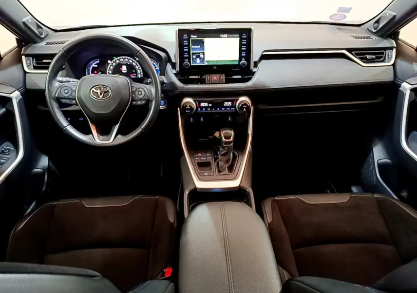 Vue intérieure frontale du tableau de bord et volant cuir noir du Toyota RAV4 gris clair avec écran tactile central et console moderne.