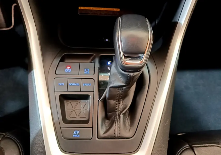 Le levier de vitesses automatique noir du Toyota RAV4 2WD 218ch Collection, vu de dessus, avec boutons de modes de conduite.