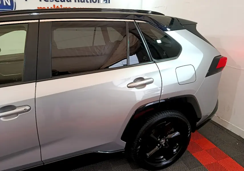 Vue latérale côté droit du Toyota RAV4 gris clair avec jantes noires et vitres teintées.