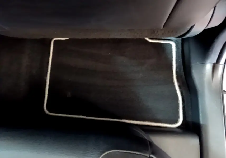Tapis de sol noir avec bordure claire au sol côté passager arrière d'un Toyota RAV4 gris clair 2019.