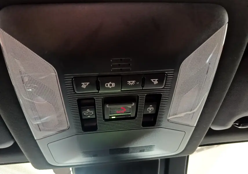 Vue en contre-plongée du panneau de commandes au plafond intérieur du Toyota RAV4 gris clair, avec bouton SOS et éclairages intégrés.