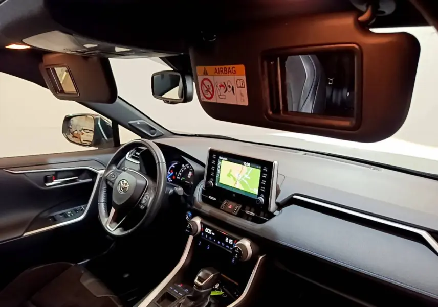 Intérieur du Toyota RAV4 2WD gris clair, vue côté conducteur, tableau de bord avec écran tactile et volant cuir.