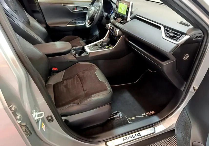 Intérieur avant droit du Toyota RAV4 gris clair 2019, sièges cuir et alcantara, tableau de bord avec écran tactile visible.