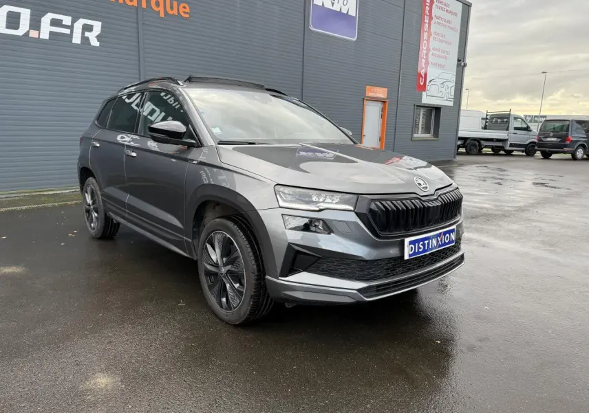 SKODA KAROQ 1.5 TSI gris graphite métallisé en 3/4 avant droit, avec jantes alliage noires et toit panoramique.