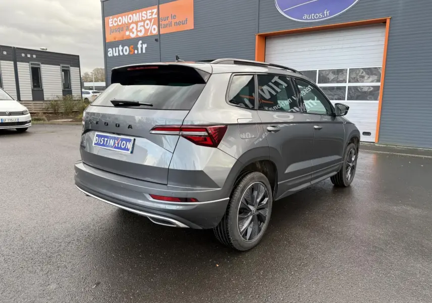 Vue 3/4 arrière droite d'un SKODA KAROQ gris graphite métallisé avec jantes alliage noires et toit ouvrant panoramique.
