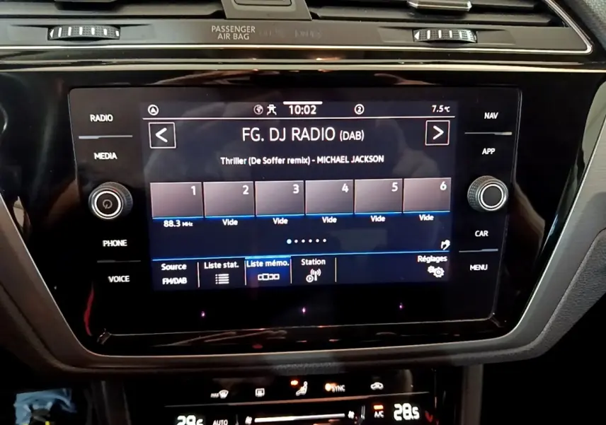 Écran tactile central du tableau de bord du Volkswagen Touran gris foncé, affichant la radio FM avec commandes autour.