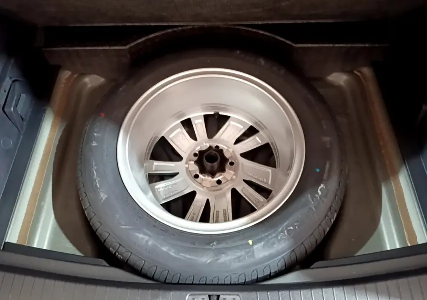 Roue de secours en jante aluminium dans le coffre du Volkswagen Touran gris foncé 2023, vue de dessus.