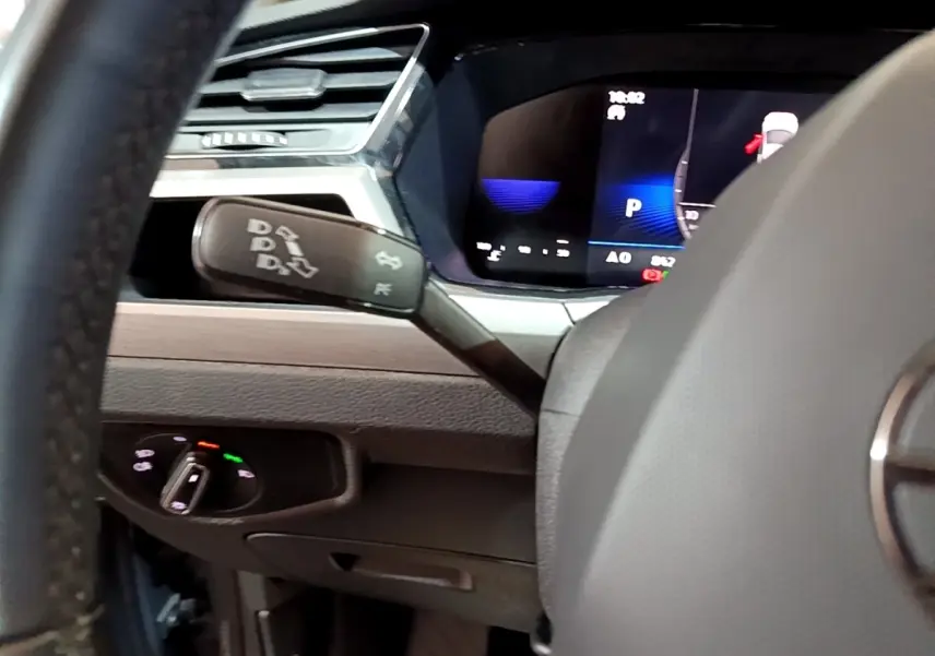 Gros plan intérieur sur le tableau de bord et levier de commande de la Volkswagen Touran 2.0 TDI gris foncé, affichage digital visible.