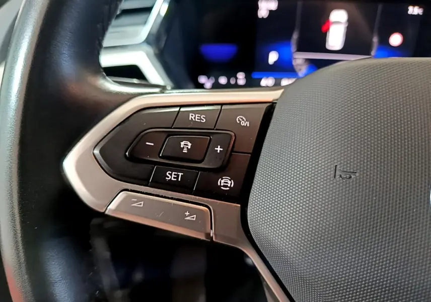 Gros plan sur les commandes du volant cuir noir du Volkswagen Touran 2023, version 2.0 TDI gris foncé.