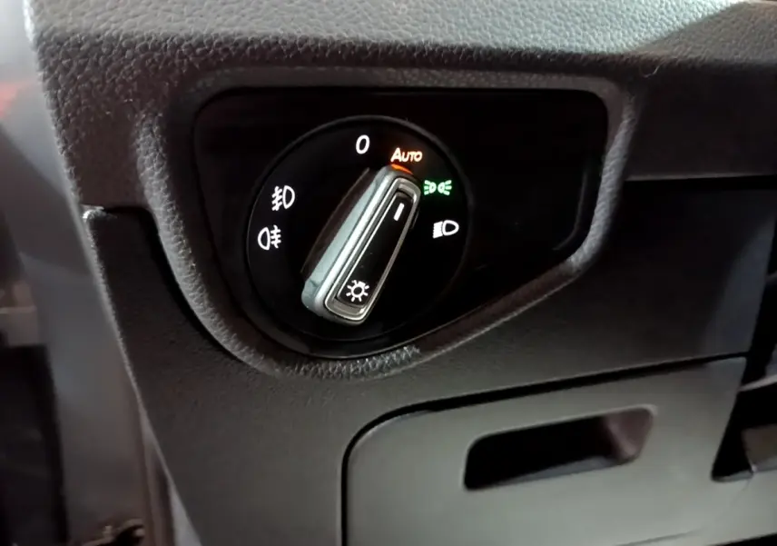 Gros plan sur le sélecteur de phares du tableau de bord du Volkswagen Touran gris foncé, mode automatique activé.