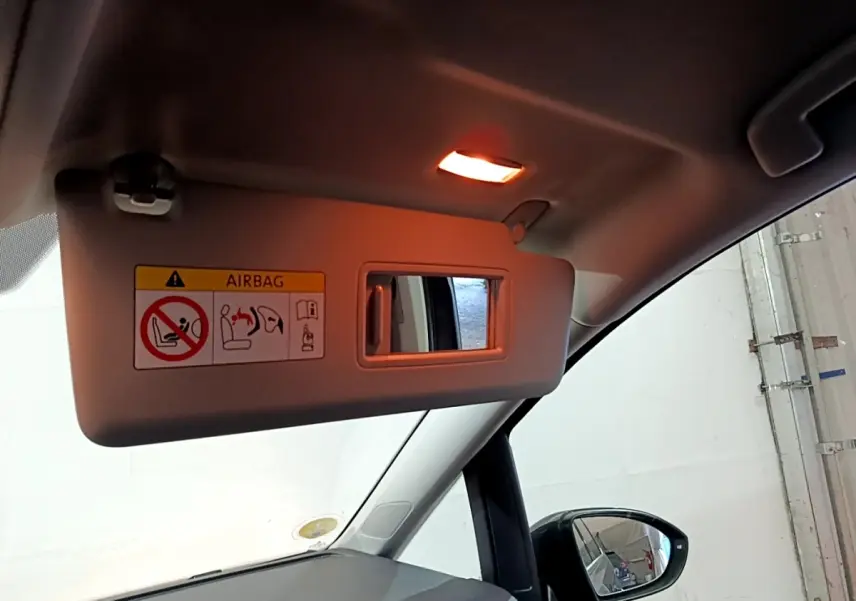 Détail du pare-soleil côté conducteur avec miroir et avertissement airbag dans un Volkswagen Touran gris foncé 2023.