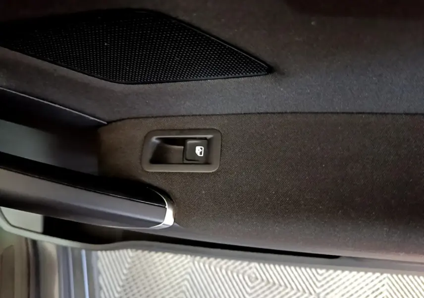 Détail de la poignée intérieure de porte arrière droite noire du Volkswagen Touran gris foncé 2023.