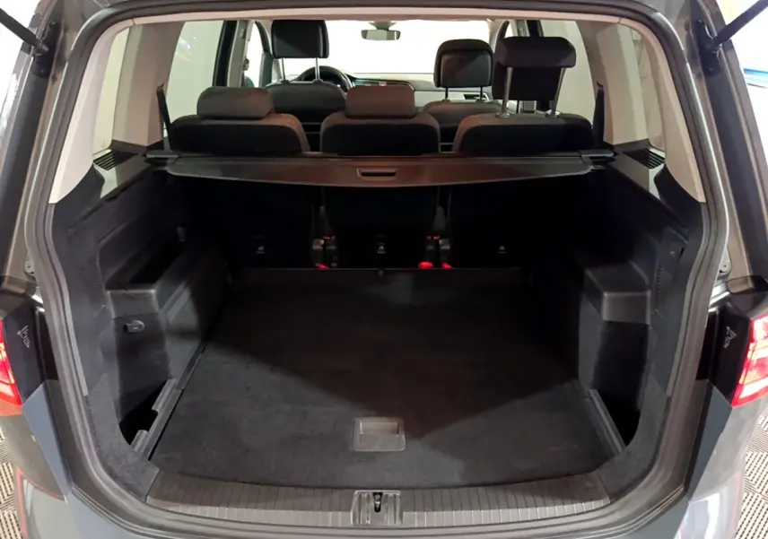 Vue arrière ouverte du coffre spacieux gris foncé du Volkswagen Touran 2.0 TDI 150 DSG7 Life Plus avec banquettes arrière visibles.