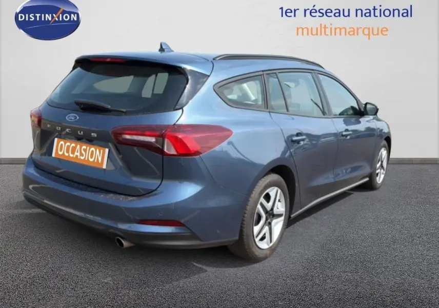 Vue 3/4 arrière droite d'une Ford Focus SW bleu foncé avec barres de toit et jantes classiques 16 pouces.